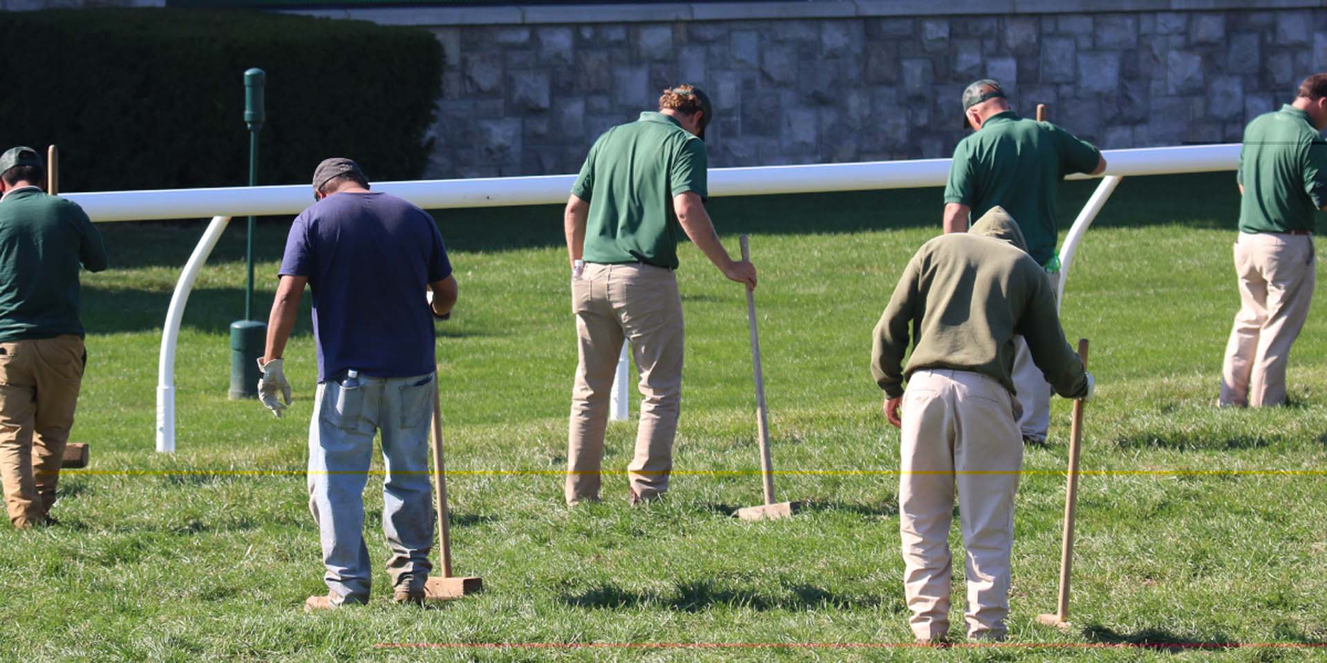 An action shot of Racetrackwin team members tamping down turf divots.